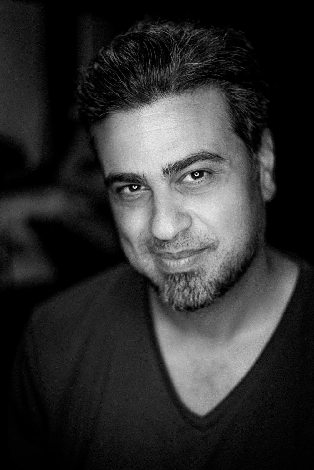Portrait of photographer Arash Afshar, captured in moody black-and-white lighting to convey trust, presence, and warmth.